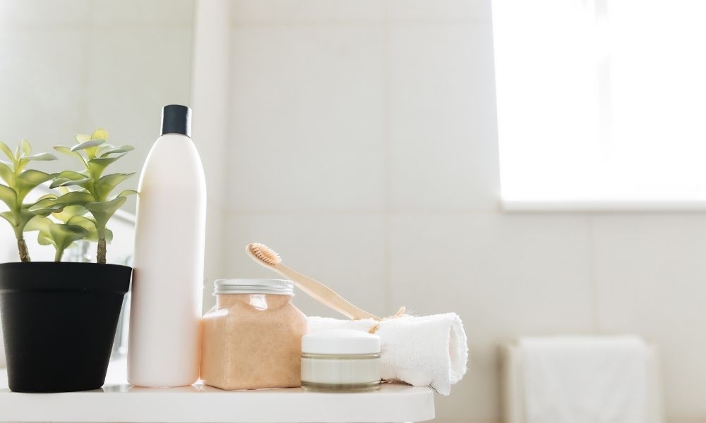 Towel, shampoo, toothbrush, bath salt bottle and cream on the bathroom countertop