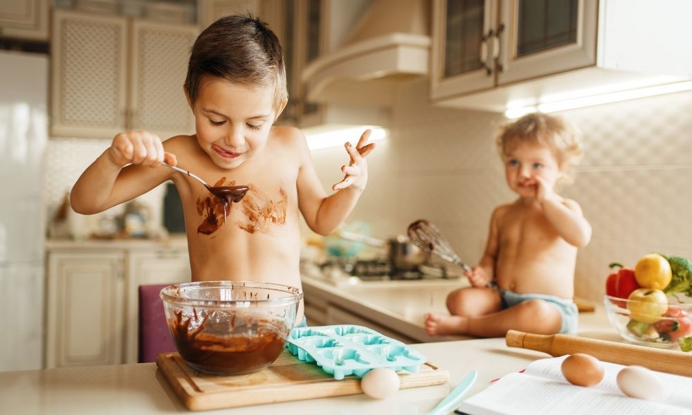 Young children playing with chocolate in the kitchen