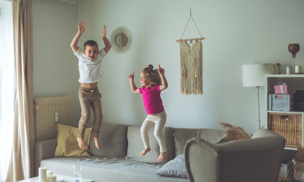 Brother and sister jumping on the sofa in the living room