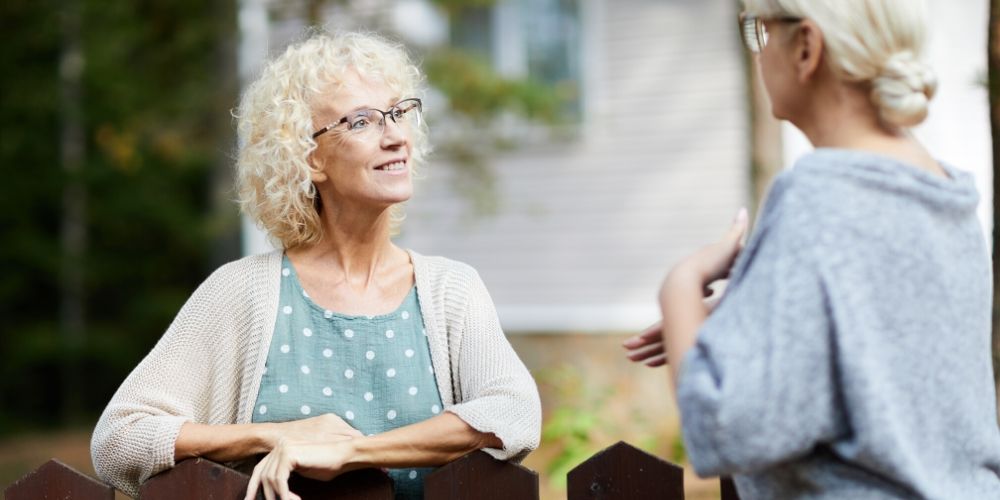 Two women neighbours chatting across the fence