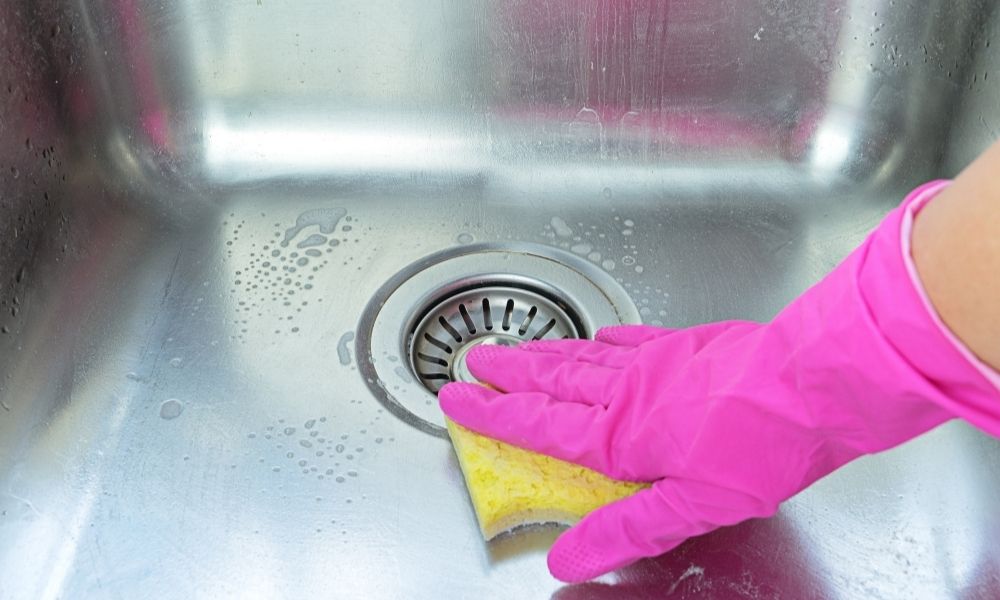 Cleaning stainless steel kitchen sink using soft sponge and soap