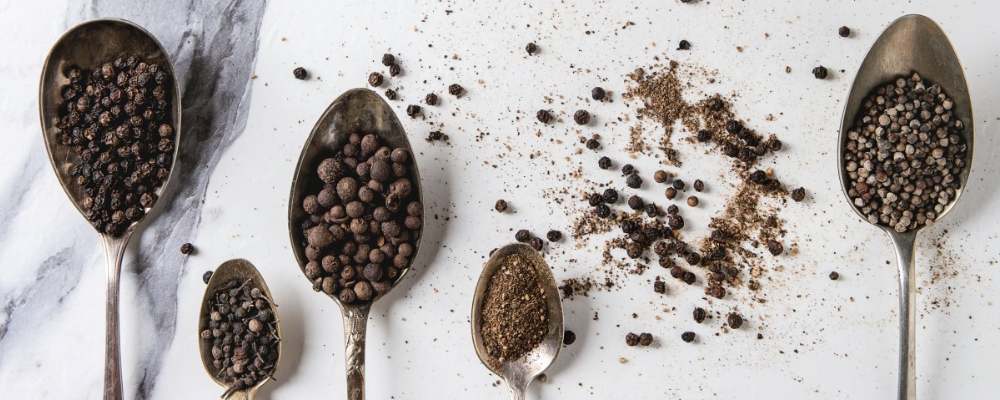 Spoonful of pepper in various forms on marble countertop