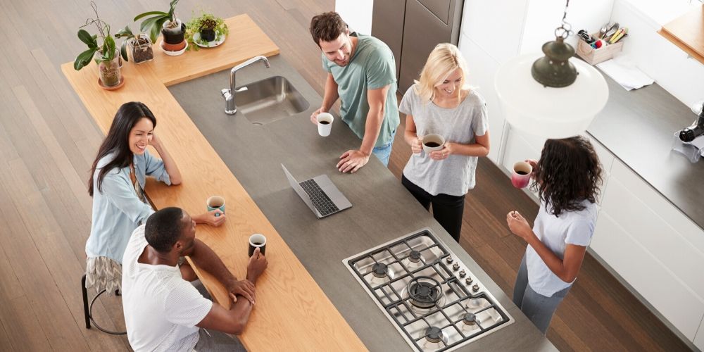 Friends drinking coffee and chatting around a sleek kitchen island