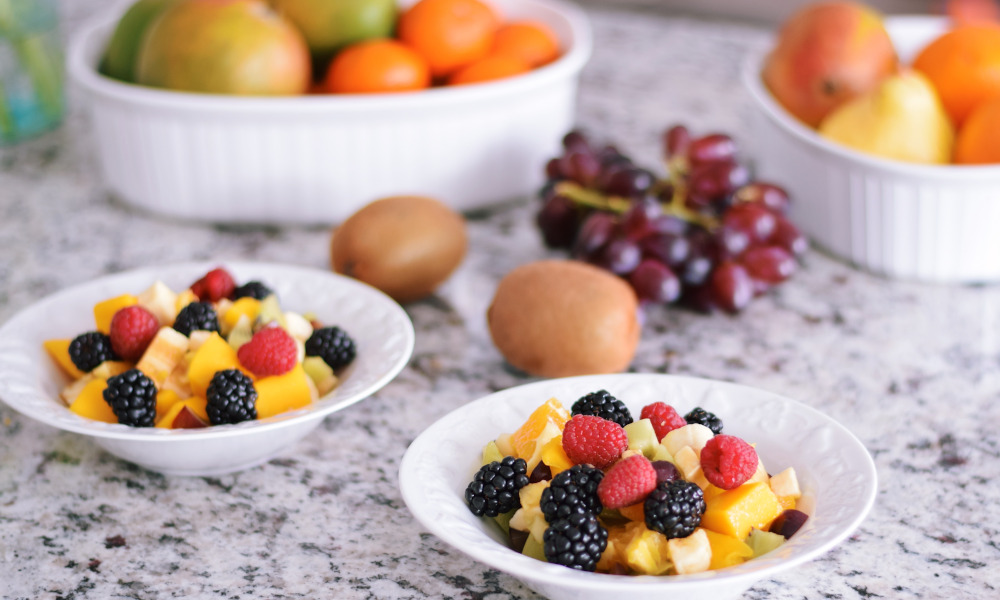 Bowls of cut fruits on a granite countertop