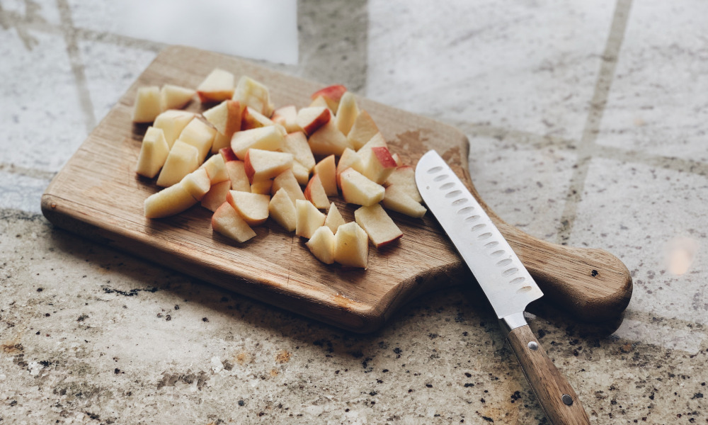 Chopped apples on wooden chopping board with knife