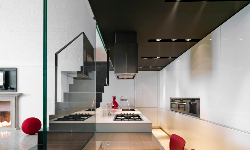 Interior view of a galley style modern kitchen with kitchen island and iron staircase