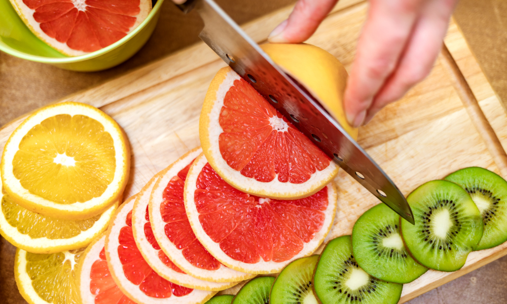 Lady cutting grapefruits with a knife on the cutting board