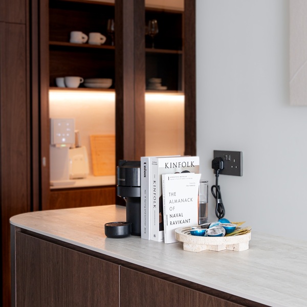 Contemporary kitchen vignette with an Aurastone surface used as a sleek bar counter, styled with books, snacks, and a coffee machine.