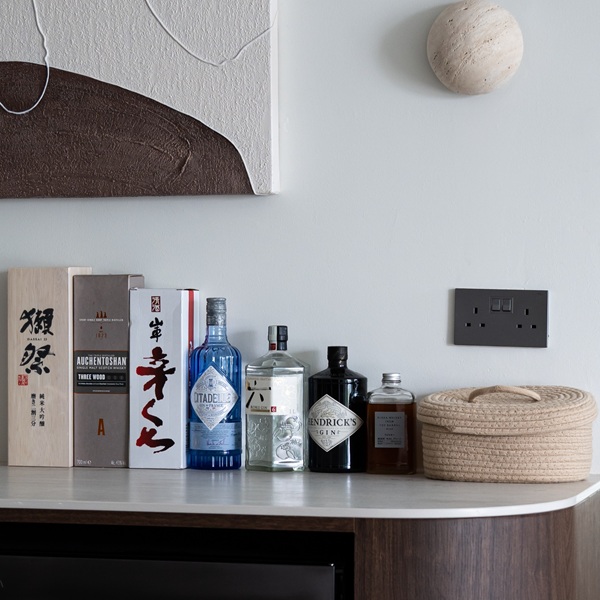 Aurastone side counter styled with premium spirits and lifestyle items, highlighting the versatility of the surface in modern living spaces.