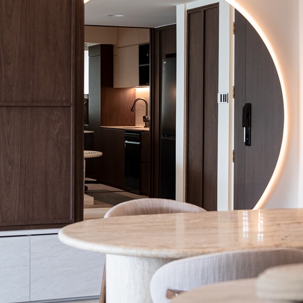 Dining and kitchen area featuring a seamless Aurastone table surface paired with curved wood cabinetry, creating a warm, modern aesthetic.