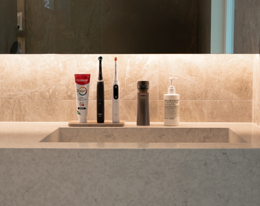 Modern bathroom vanity featuring an integrated Aurastone sink and countertop in a soft beige tone, styled with everyday essentials under warm ambient lighting.