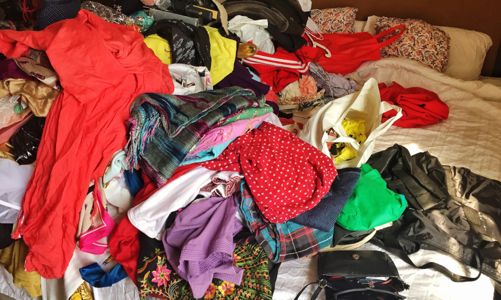 A bed full of messy clothes in preparation for decluttering