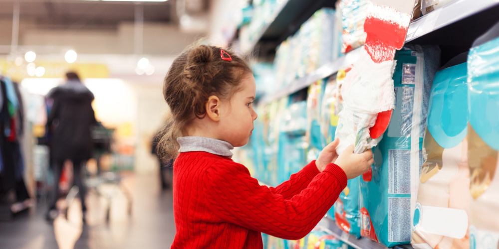 Little girl selects diapers in supermarket.