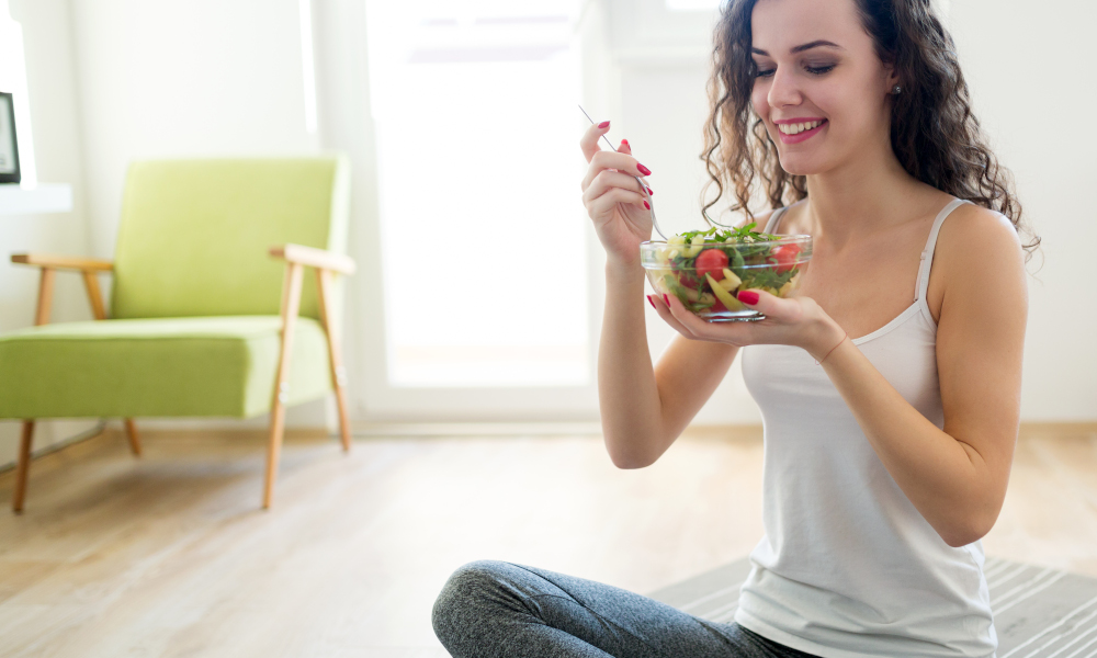 Fitness young woman staying healthy eating a salad after exercise