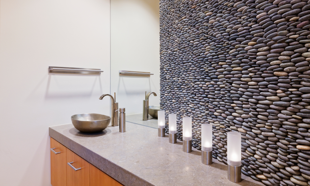 Elegant modern bathroom with quartz stone countertop, stainless steel bowl sink and pebble stone wall