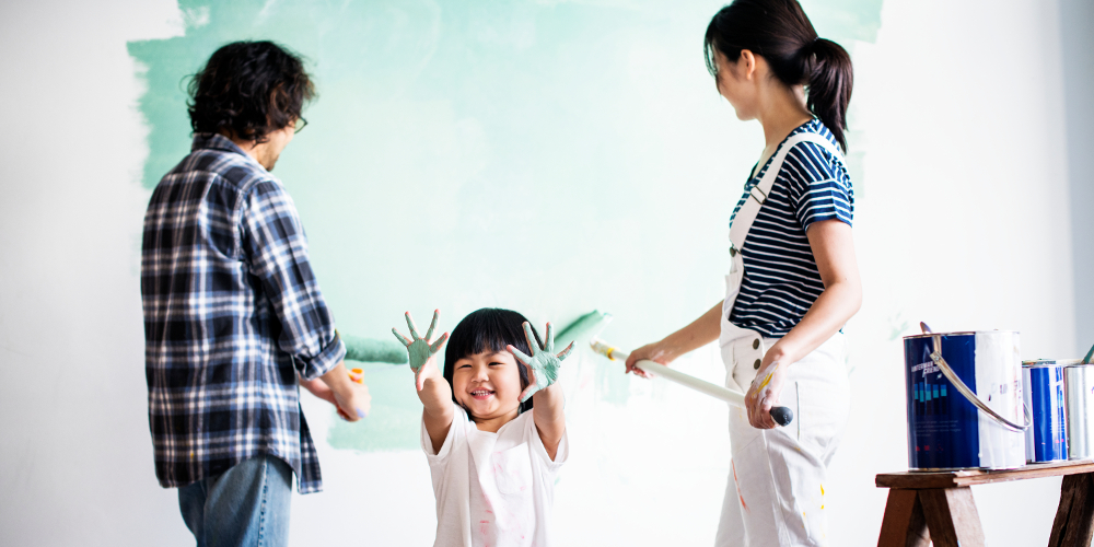 Asian family painting wall with child playing with paint