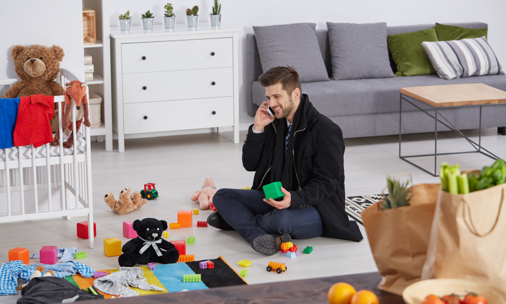 Happy single father sitting on a floor with children toys in the playroom