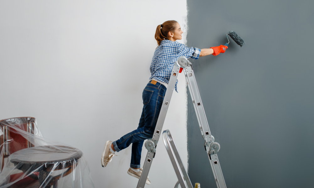 Female house painter in gloves paints the wall. Home repair, laughing woman doing apartment renovation, home renovation