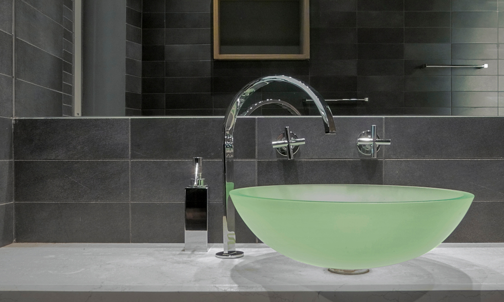 A light green glass countertop washbasin and steel tap in the modern bathroom