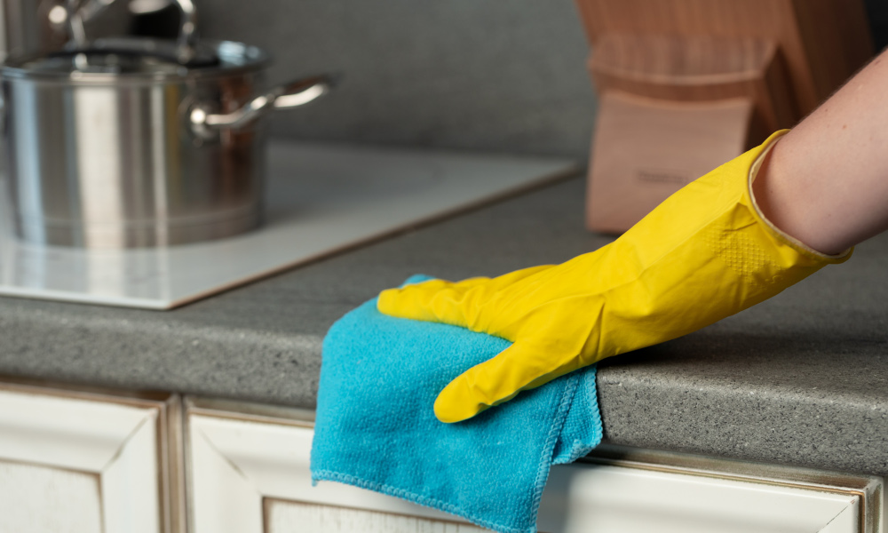 Hand in yellow glove cleaning old kitchen countertop