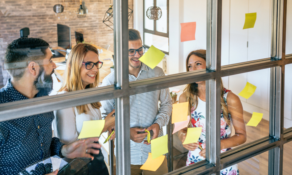 Happy business people brainstorming ideas and collaborating using sticky notes