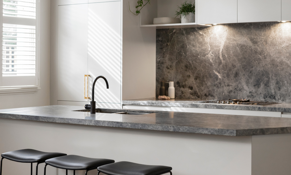 Matching stone backsplash wall with kitchen countertop and island surface