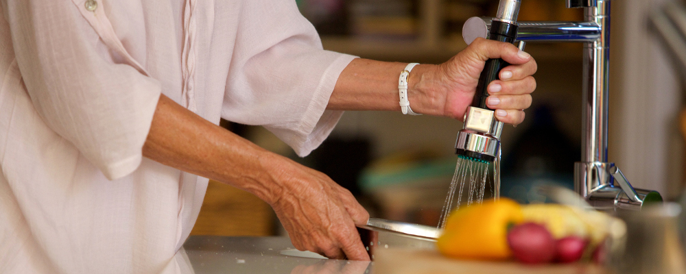 lady washing kitchen utensils using pull-out faucet with black hose