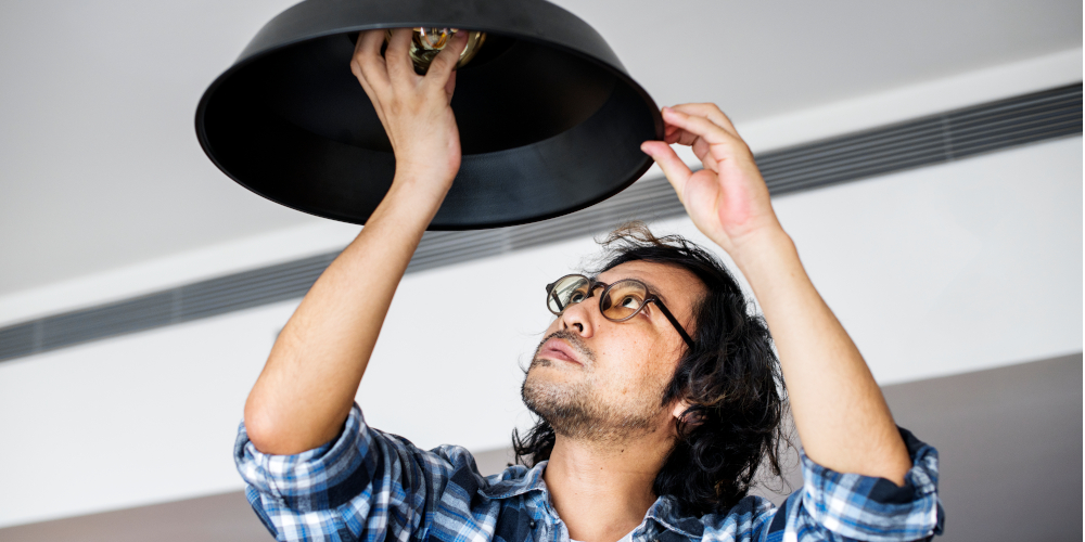 Man changing fused lightbulb with energy saving light bulb