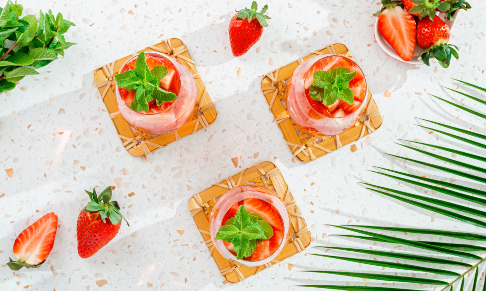 Palm leaf and strawberry smoothies flat lay on terrazzo countertop