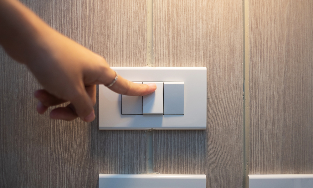 Female finger is turn on or off on light switch on white wall at home. Energy Saving, power, electrical and lifestyle concepts