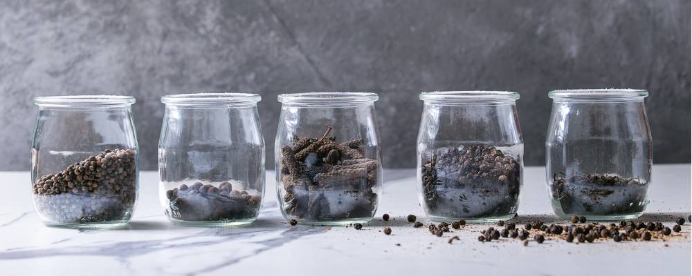 Black pepper in jars on marble countertop