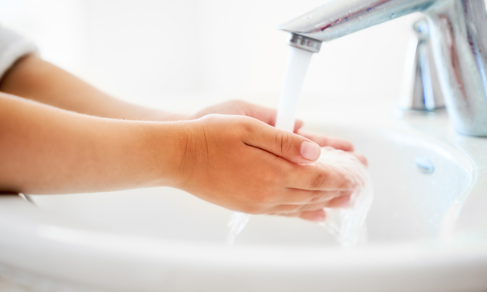 Child is washing hands under running water and soap to stay clean and healthy