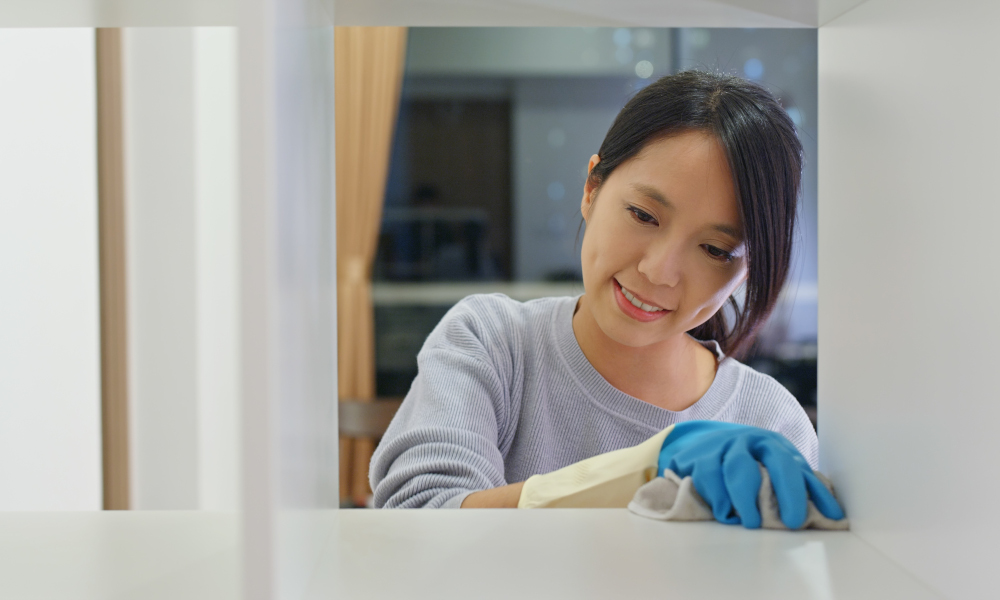 Woman spring cleaning the kitchen cabinet at home