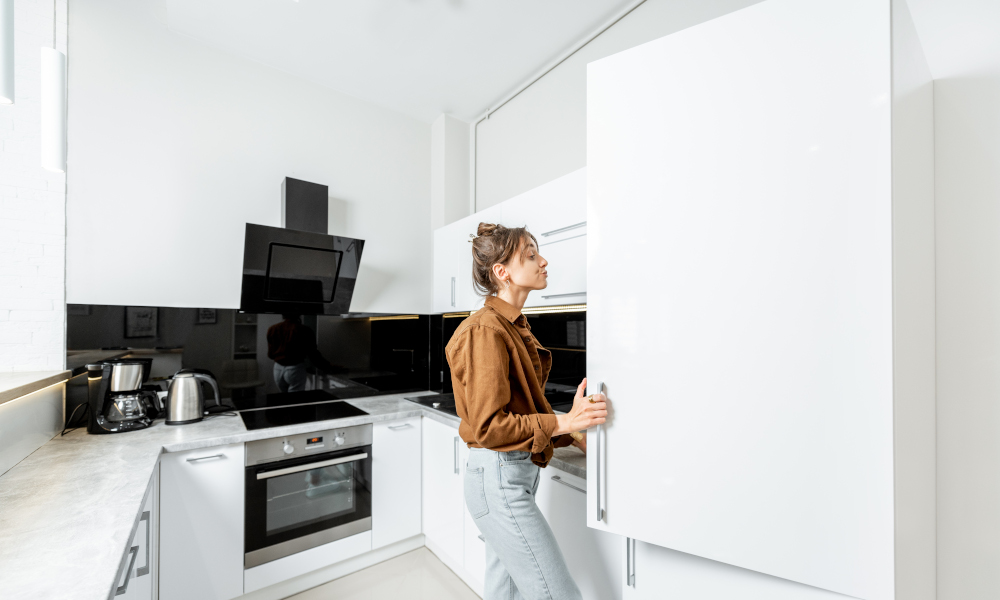 Woman opening a spacious kitchen cabinet in white