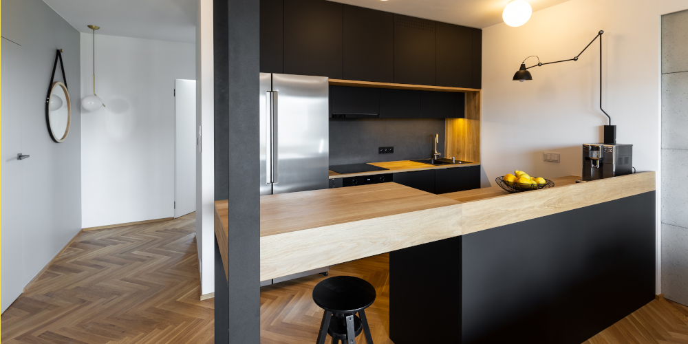 Stool under beige countertop in black kitchen interior with lights and lamp