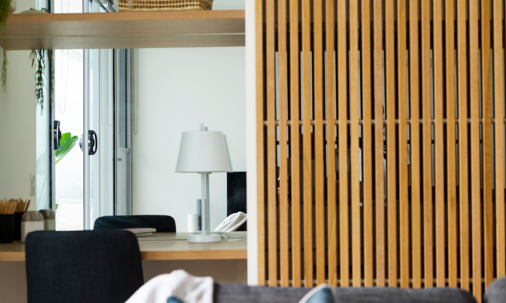 Wooden wall partition with wooden shelving unit separating home office and living room