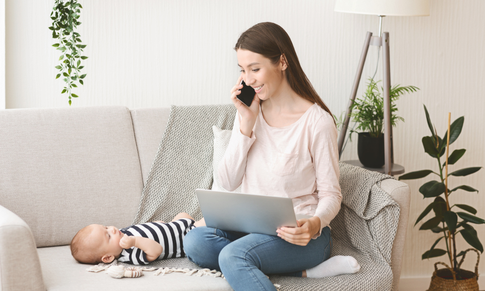 Busy young mother working from home while tending to newborn baby