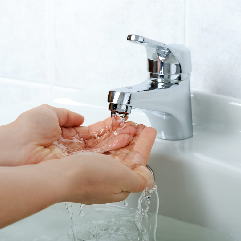 Hands close-up with flowing water from sink faucet