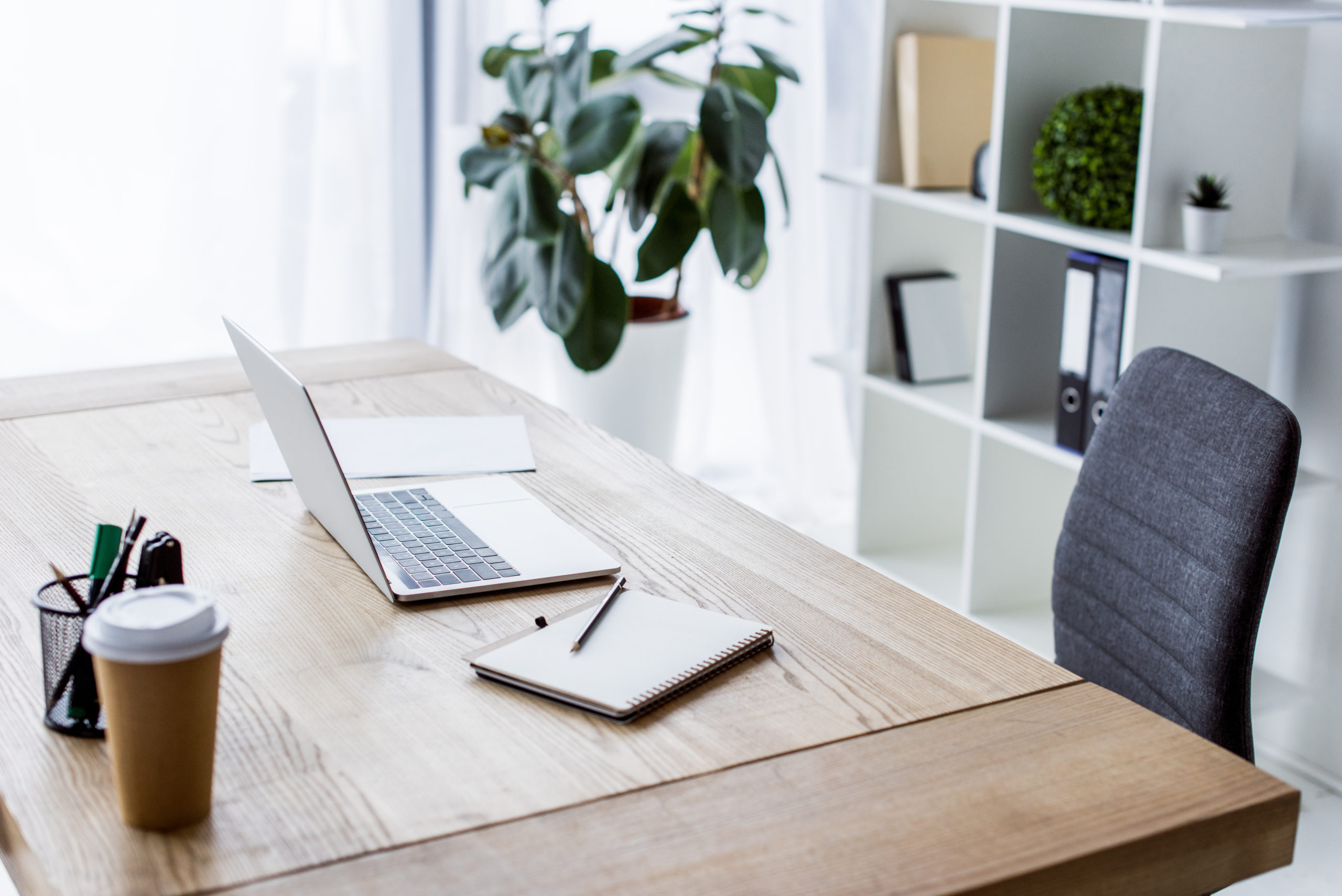 laptop and coffee in paper cup on table in business workspace