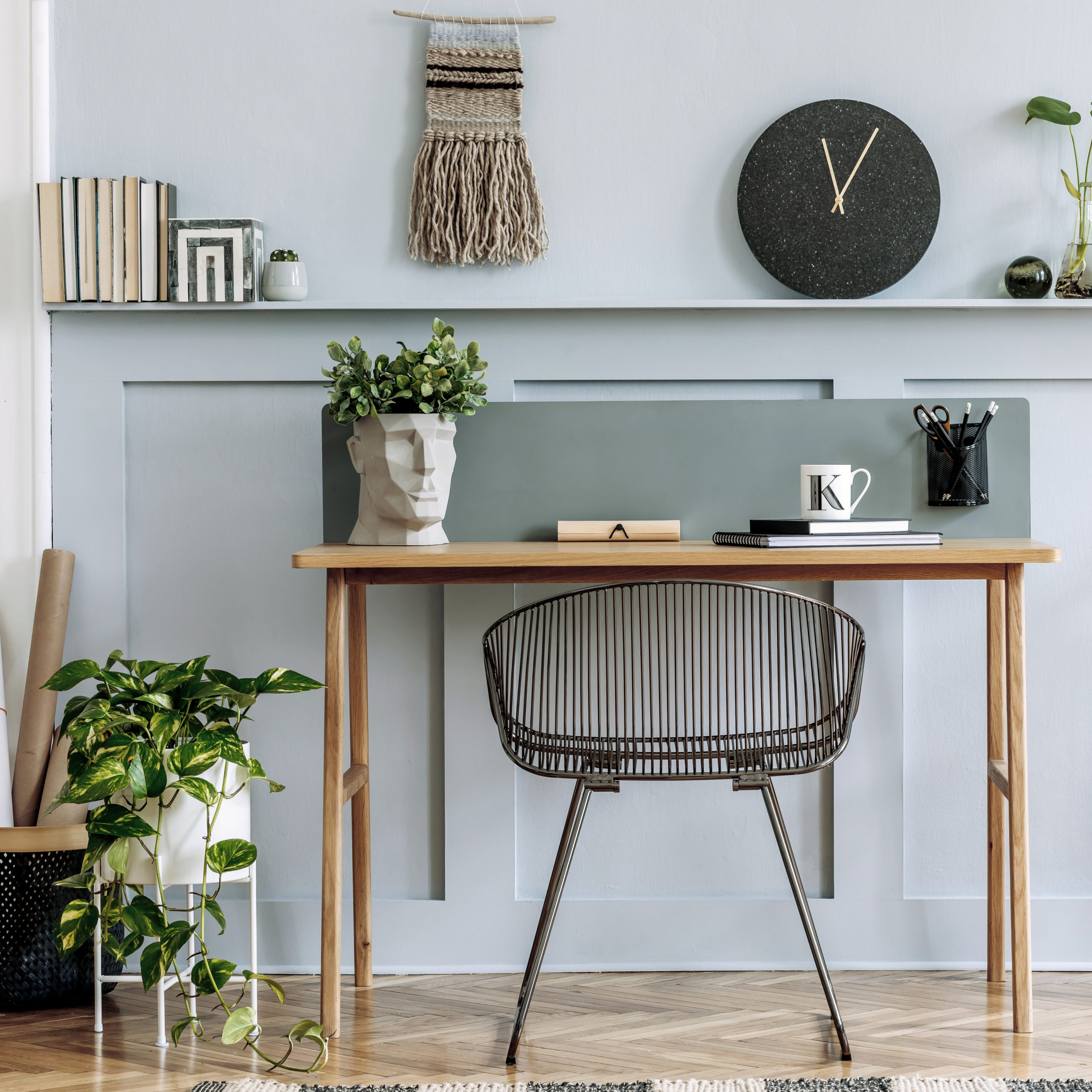 Scandinavian interior design of home office space with wooden desk, modern chair, wood paneling with shelf, plant, carpet, bicycle, office supplies and elegant personal accessories.