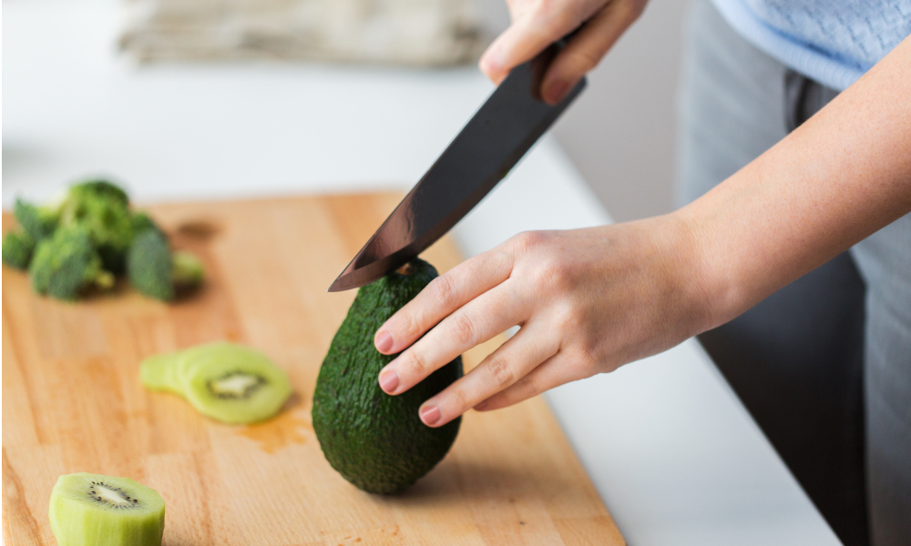 Woman cutting an avocado using a chopping board